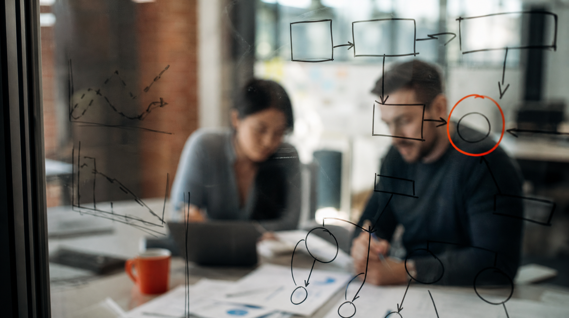 Two colleagues work through forecasting and churn predictions on a glass board.