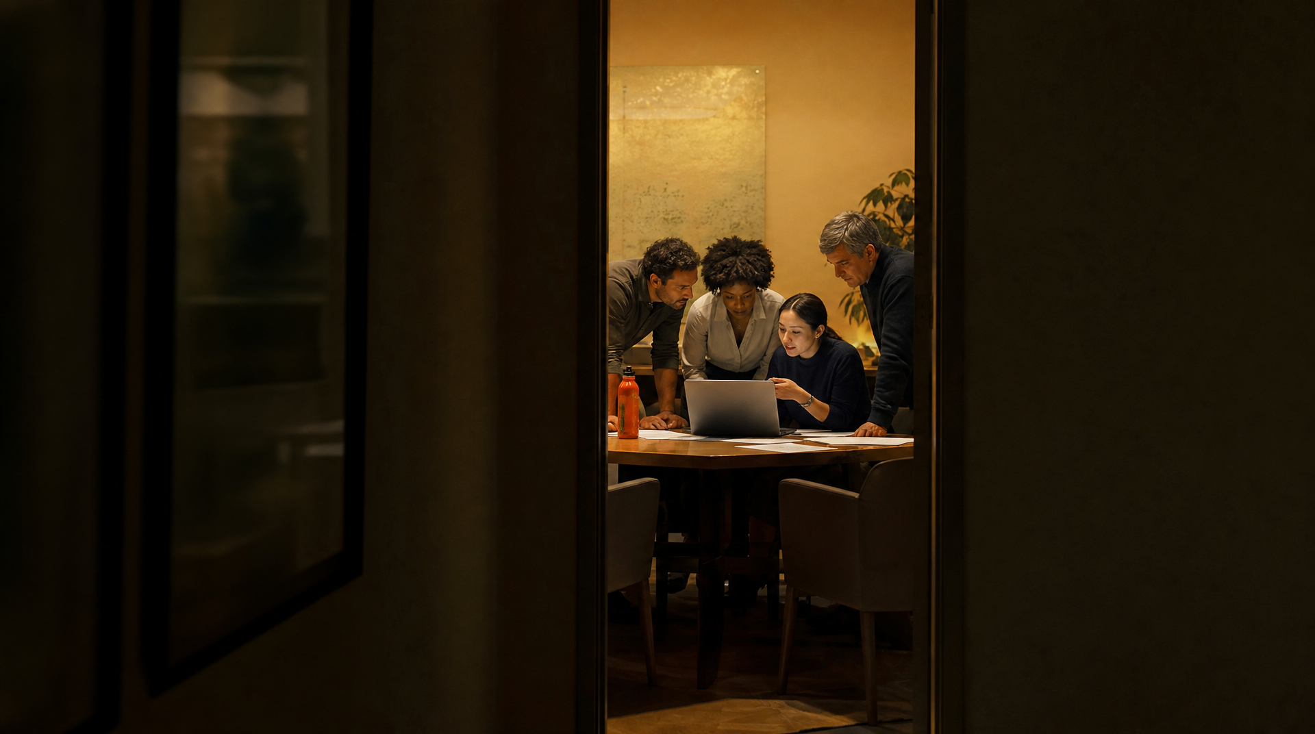 A manager and team gather around a laptop, sharing how they use an AI assistant.